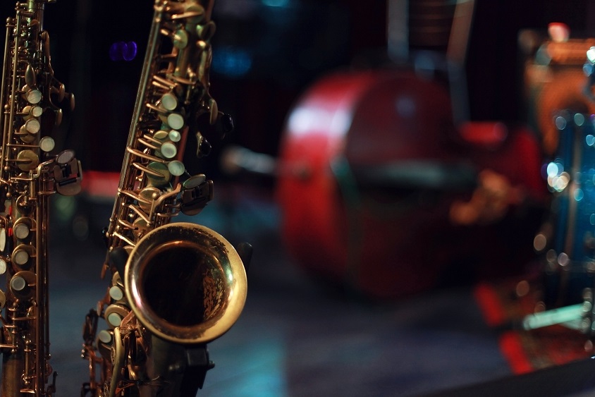 Saxophones dorés en gros plan avec une contrebasse floue en arrière-plan dans un studio musical.