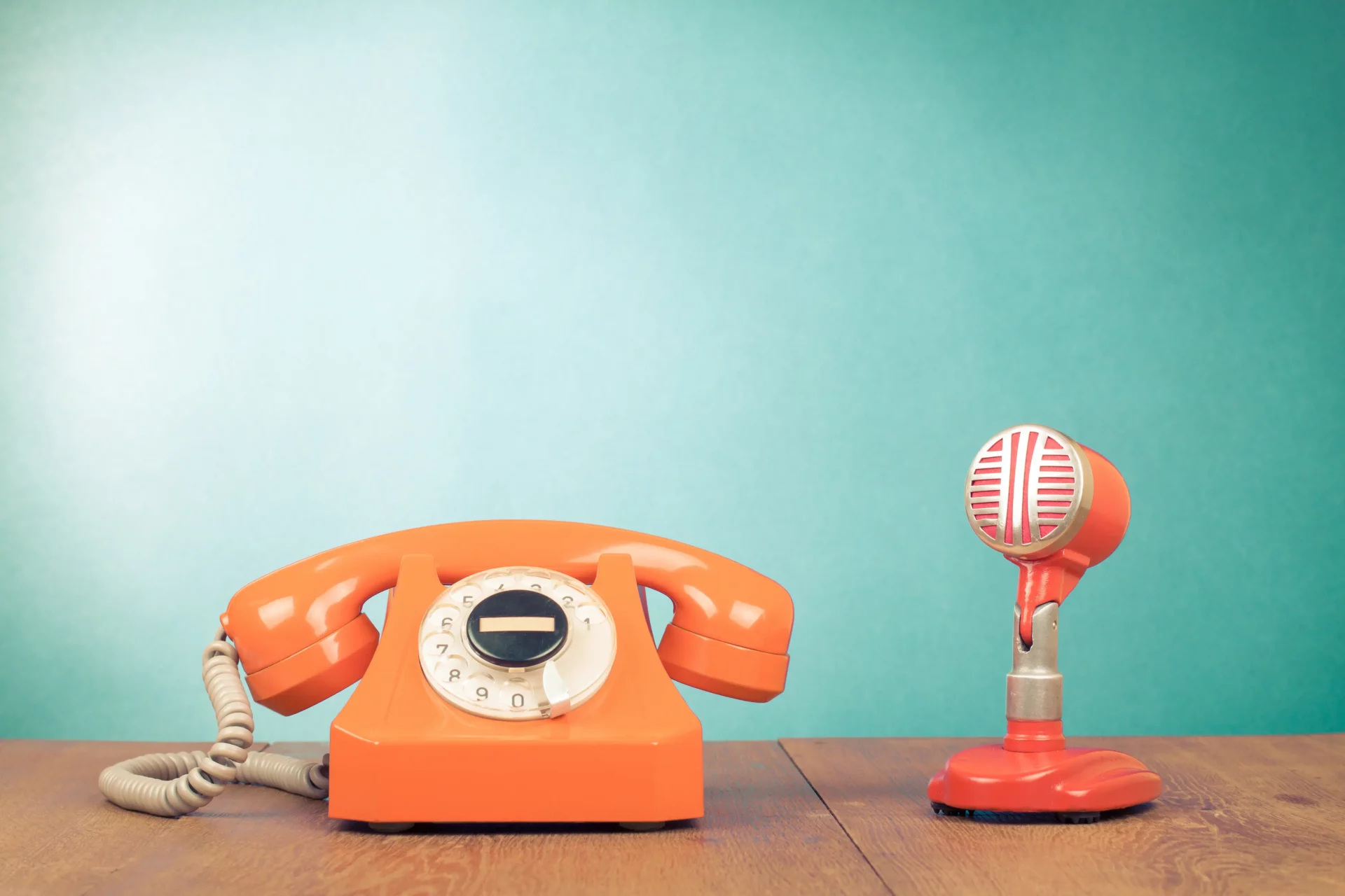 Téléphone à cadran rotatif orange et microphone vintage sur fond bleu