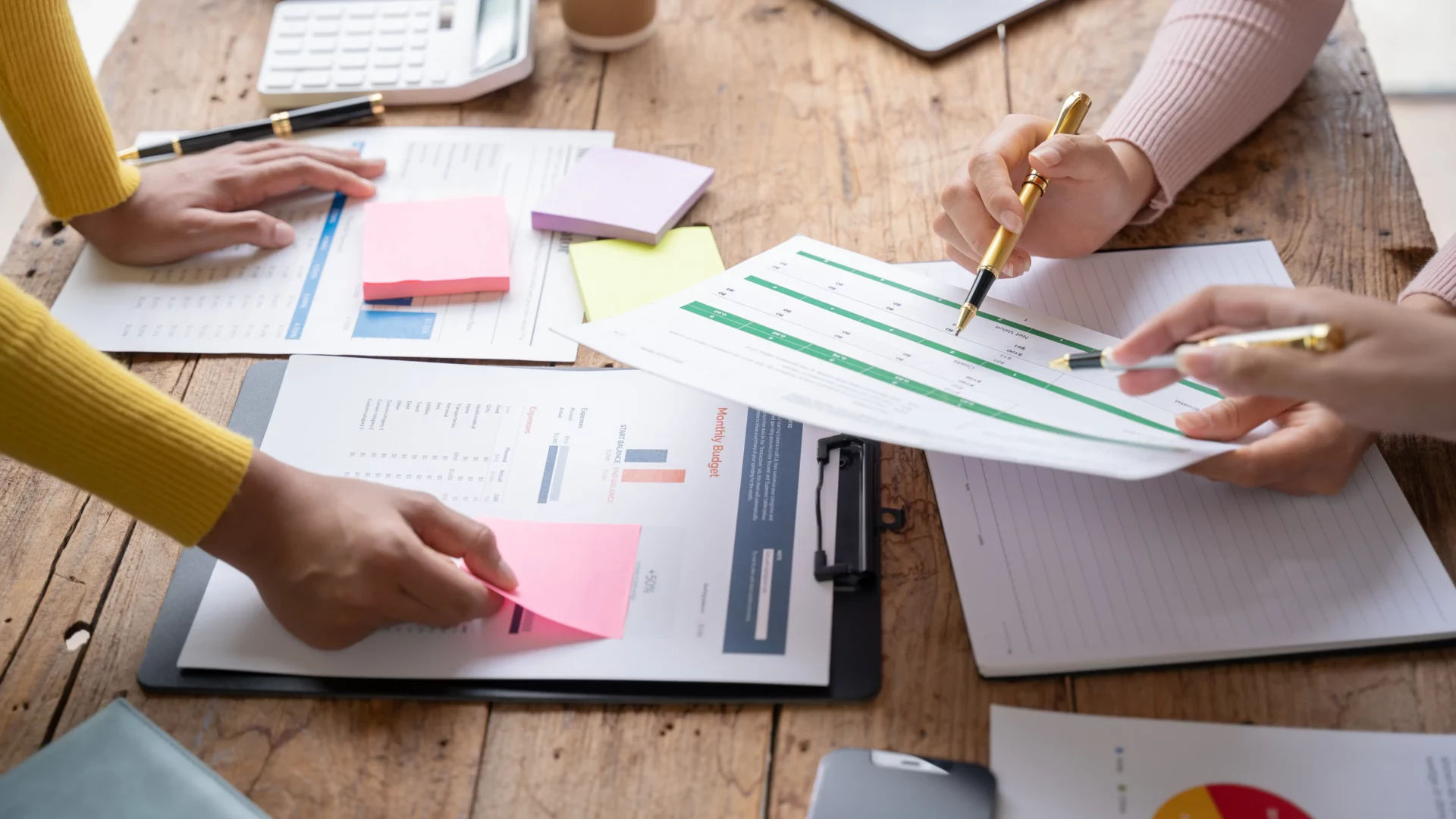 Des collègues travaillant ensemble avec des documents et des notes pour planifier un message de répondeur efficace.