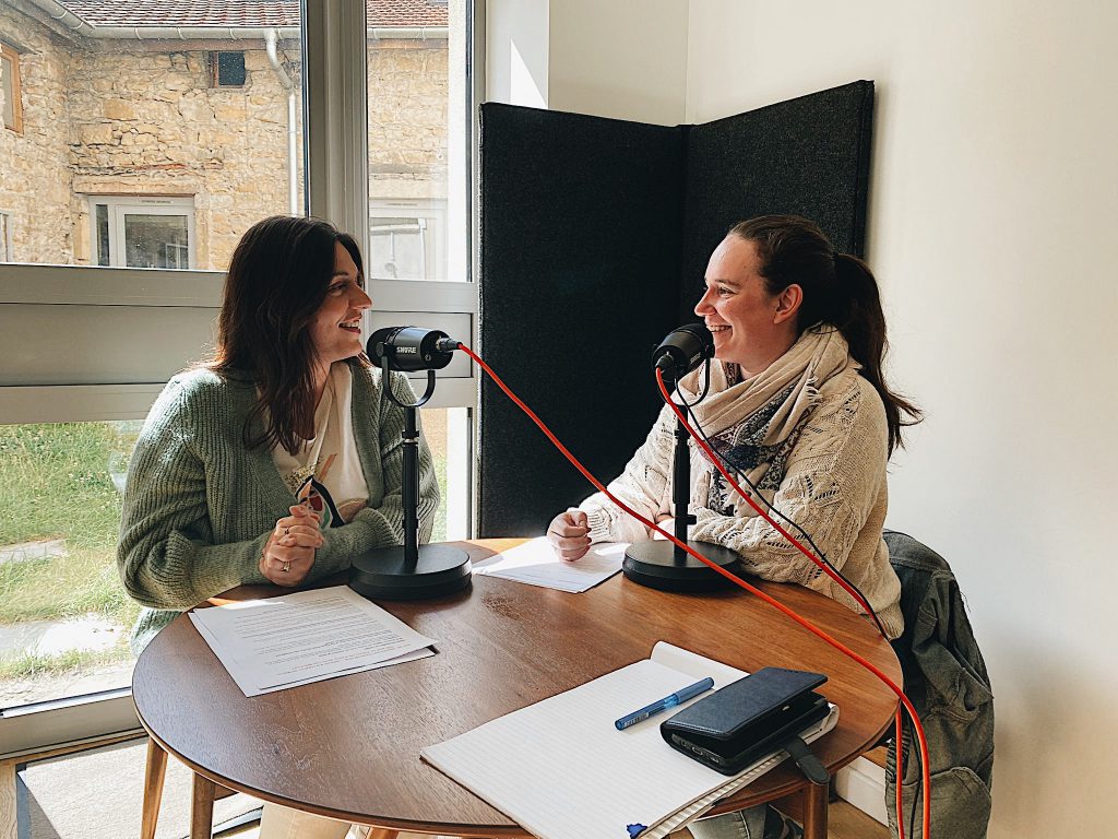 Deux personnes enregistrant un podcast dans un studio, discutant face à un microphone.