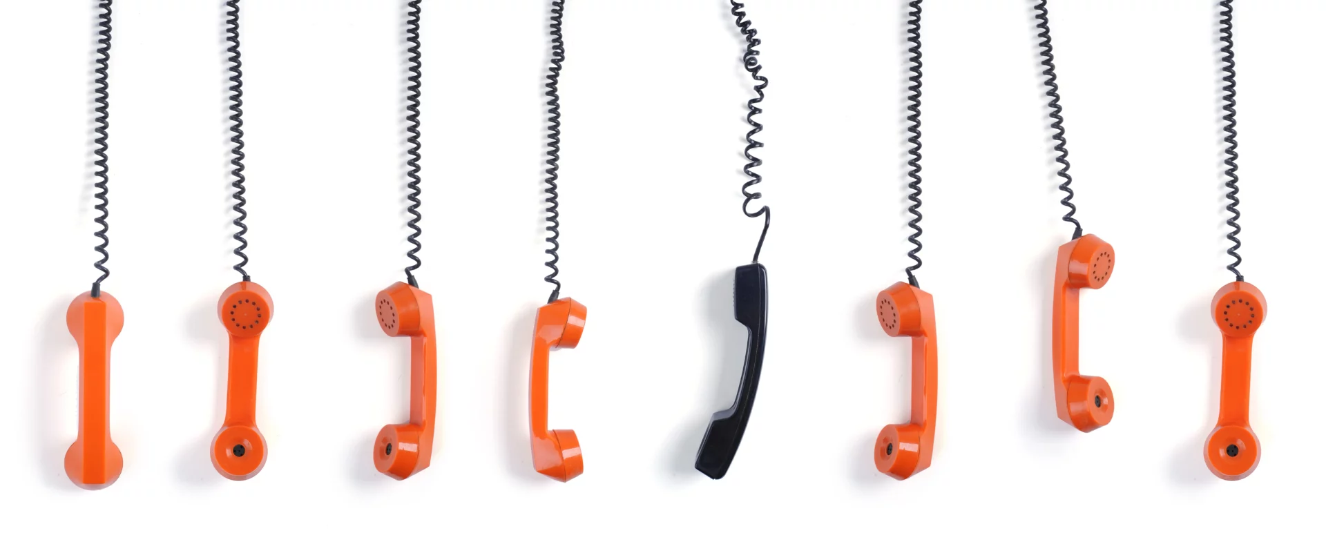 Plusieurs combinés de téléphones rétro orange et noir suspendus, symbolisant un accueil téléphonique.