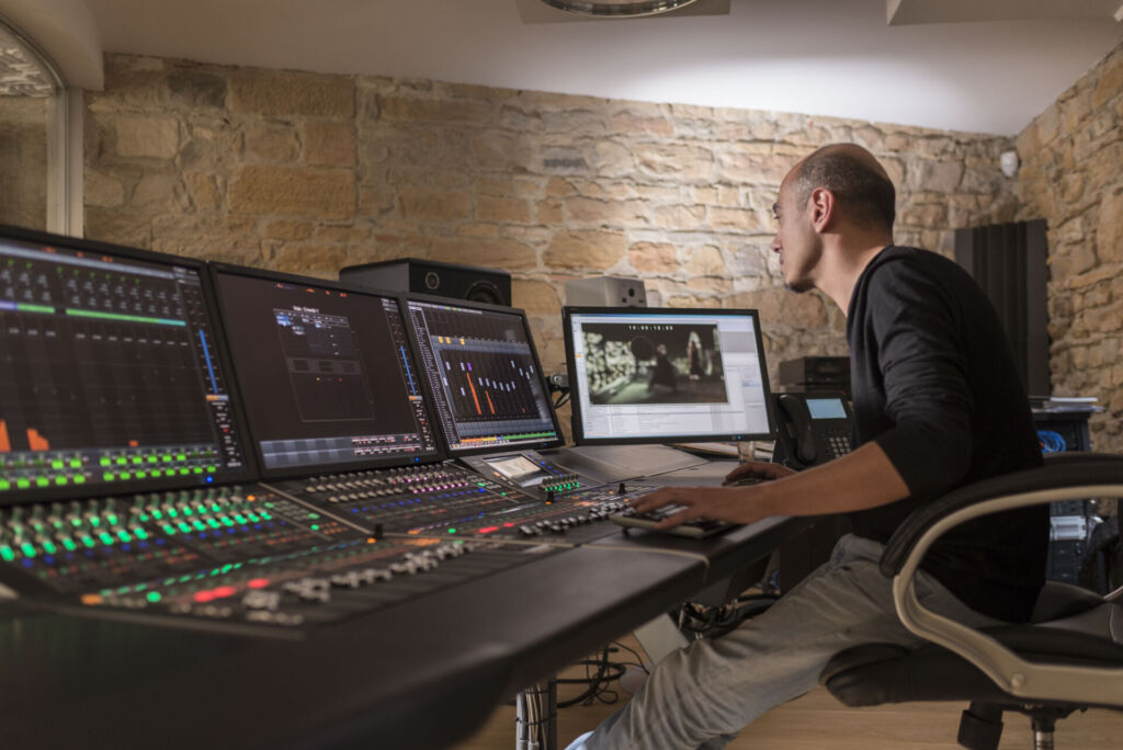 Un sound designer travaillant sur plusieurs écrans dans un studio de sonorisation