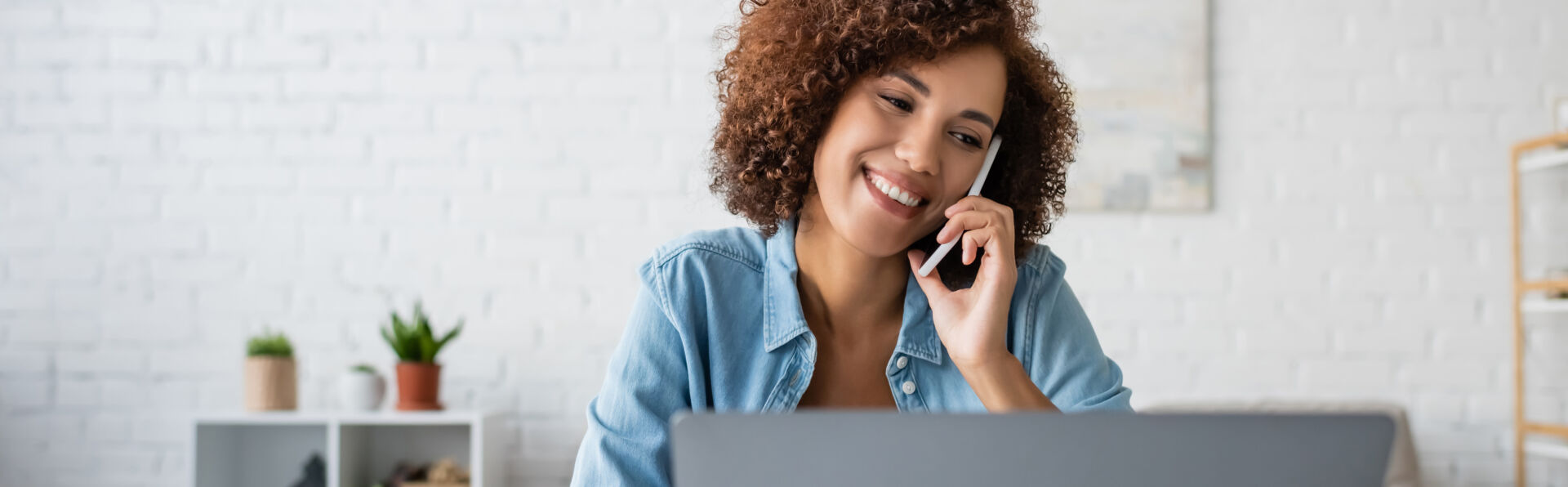 Une femme parlant au téléphone portable près d'un ordinateur portable flou à la maison, bannière, image de stock