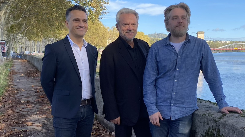 Trois hommes se tenant debout devant la caméra pour représenter le "Groupe ATS".