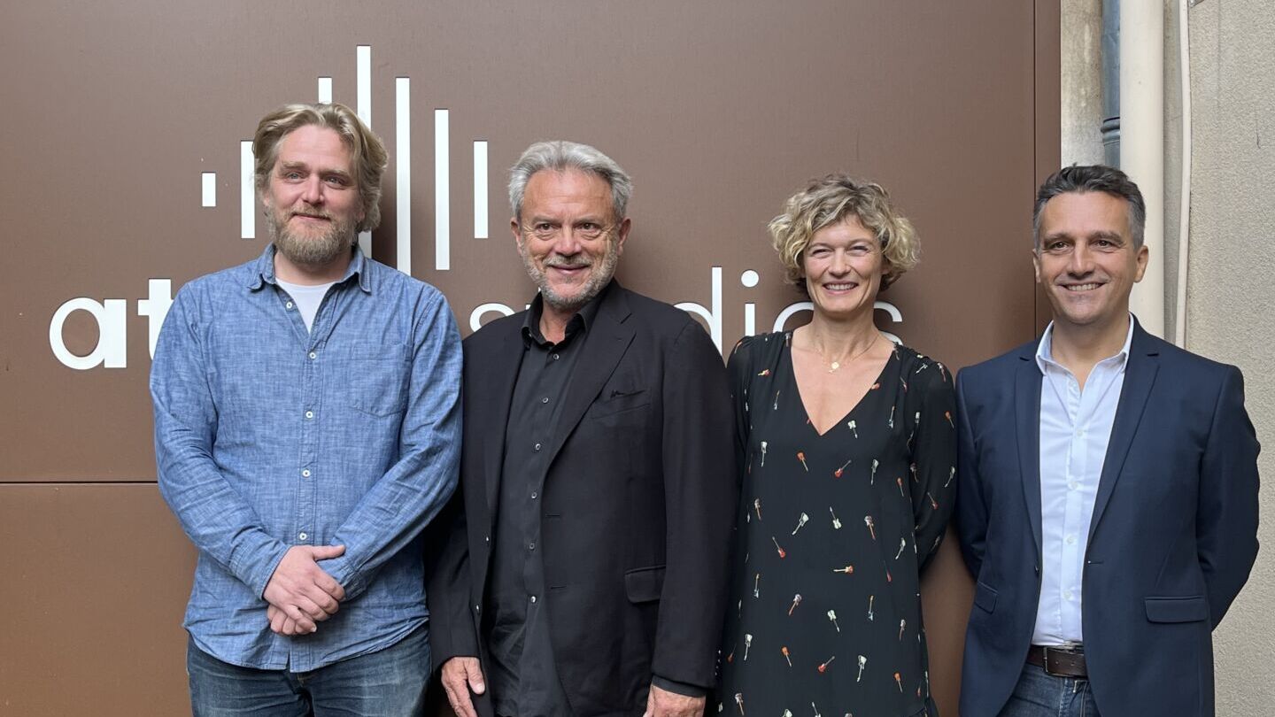 Trois hommes et une femme travaillant chez ATS Studios pose pour une photo dans la cour des locaux.