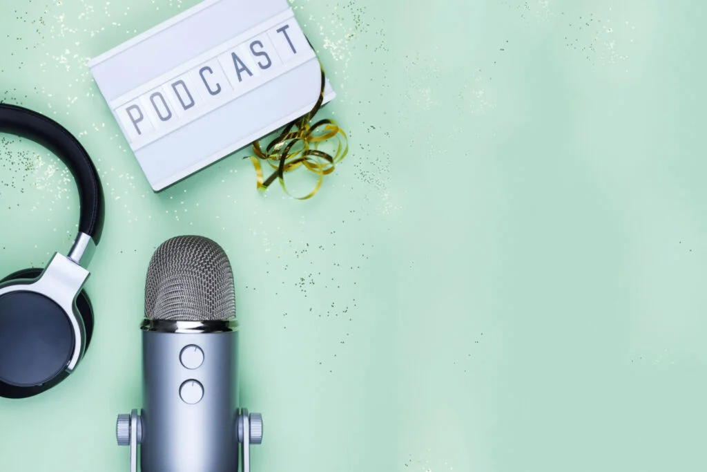 Casque audio, microphone et panneau lumineux indiquant "Podcast" sur un fond vert avec des confettis dorés 