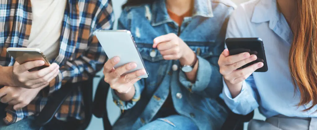 Trois personnes utilisant des smartphones, représentant l'importance de l'accueil téléphonique dans la communication moderne