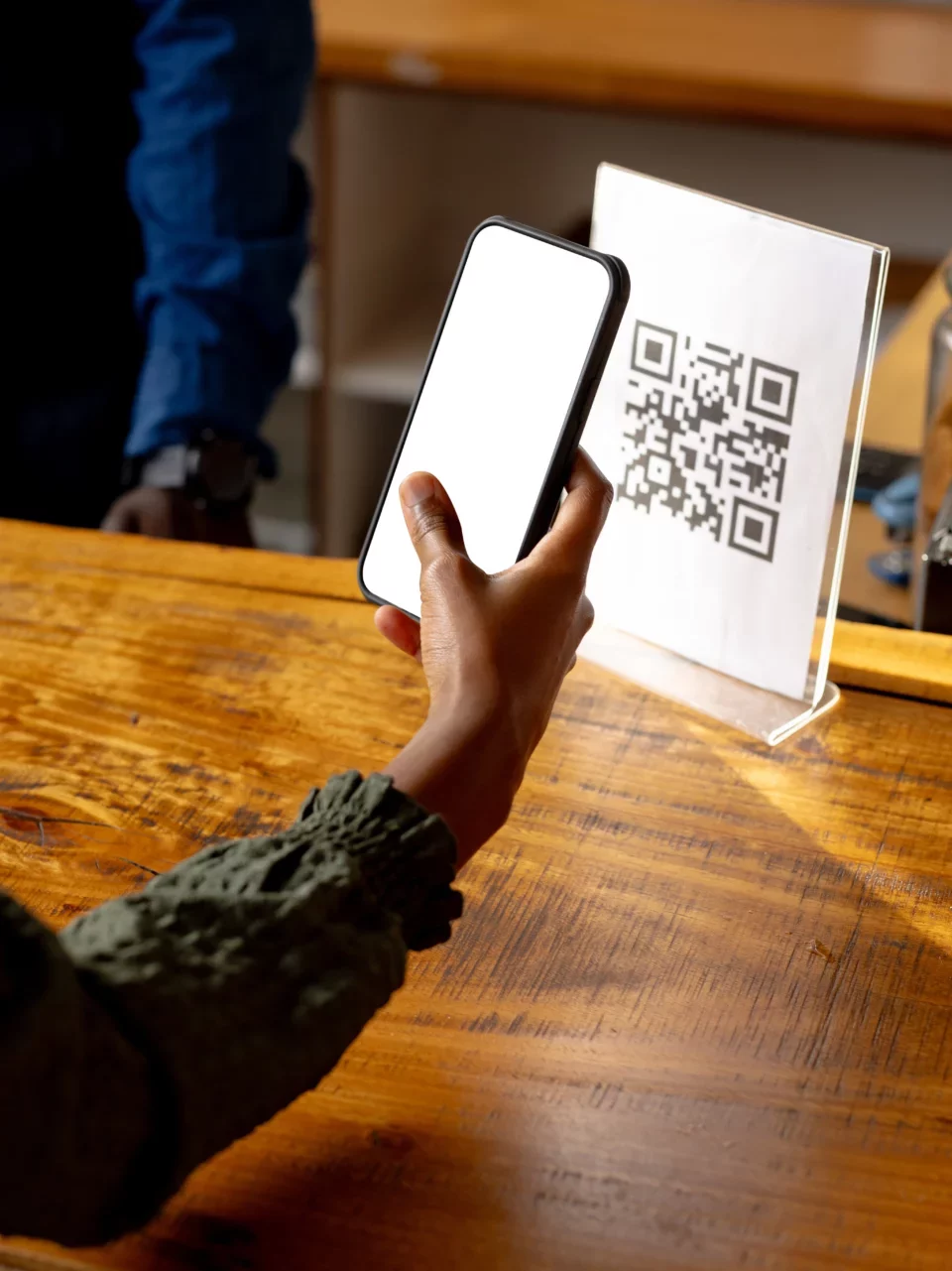 Personne scannant un QR code placé sur un bureau avec un smartphone.