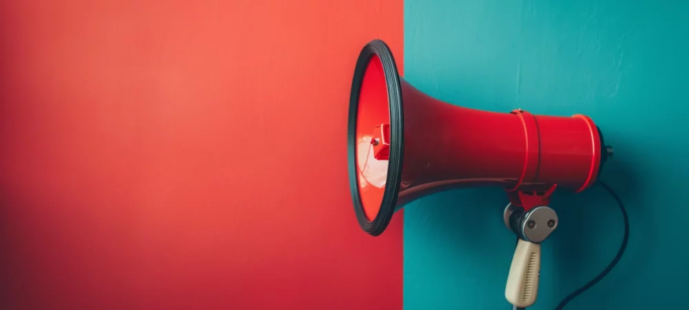 Mégaphone rouge sur fond divisé en rouge et bleu, symbolisant la communication sonore pour PME