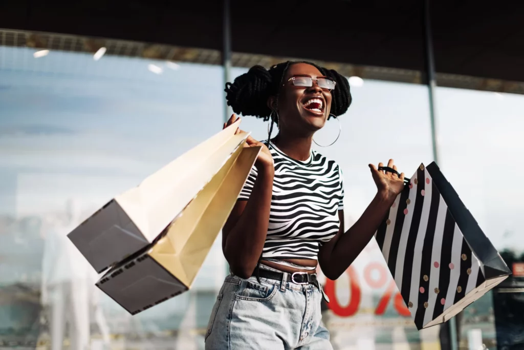  Femme souriante avec des sacs de shopping devant un magasin 