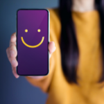 Personne tenant un smartphone avec un visage souriant à l'écran, symbolisant une expérience client positive.