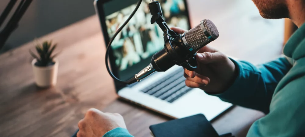 Personne utilisant un microphone et un ordinateur pour produire un podcast professionnel