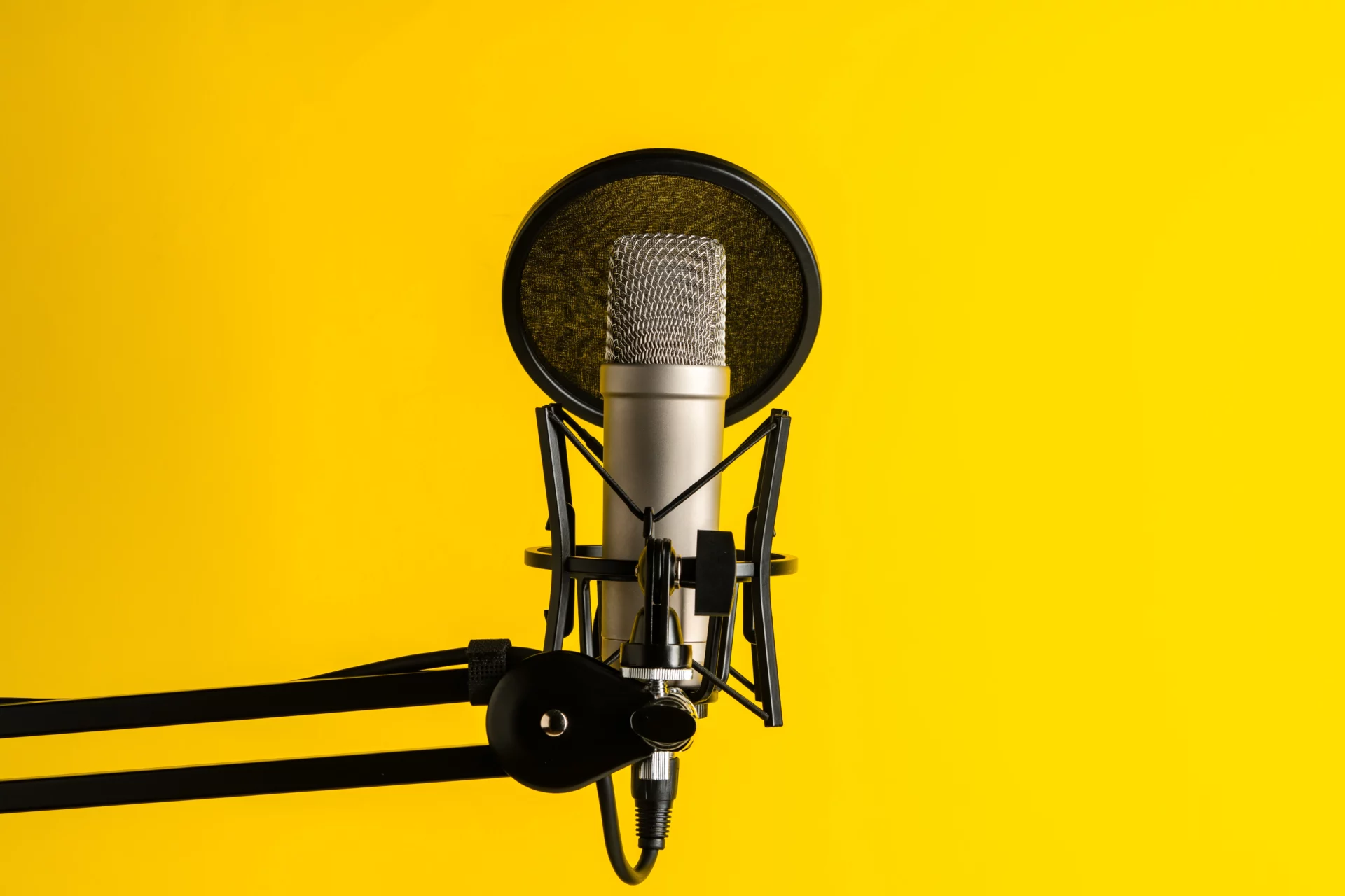 Microphone professionnel sur fond jaune utilisé pour la création de podcasts professionnels