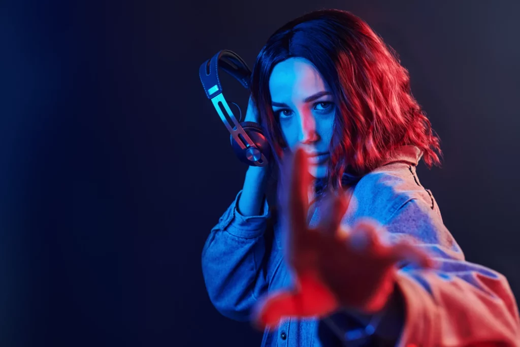 Jeune femme portant un casque audio sous une lumière bleue et rouge, illustrant l'impact émotionnel du son.